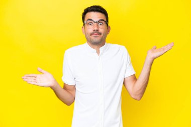 Soyutlanmış sarı arka planda genç yakışıklı bir adam şüpheli hareketler yapıyor.