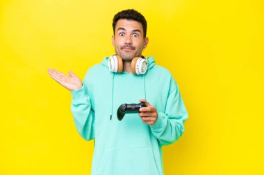 İzole edilmiş duvarın üzerinde video oyunu kontrolörüyle oynayan genç yakışıklı adam ellerini kaldırırken şüpheye düşüyor.