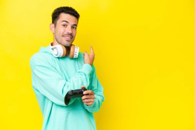 Genç yakışıklı bir adam video oyunu kontrolörüyle oynuyor izole duvarın arkasında.