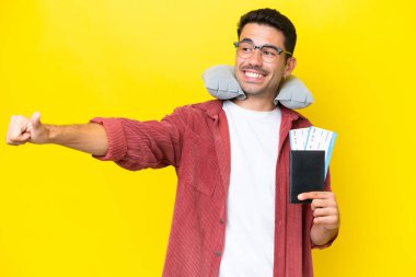 Şişirilebilir Seyahat Yastığı 'na sahip genç yakışıklı adam izole edilmiş sarı arka planda baş parmak hareketi yapıyor.