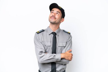 İzole edilmiş beyaz arka planda genç güvenlik görevlisi gülümserken yukarı bakıyor