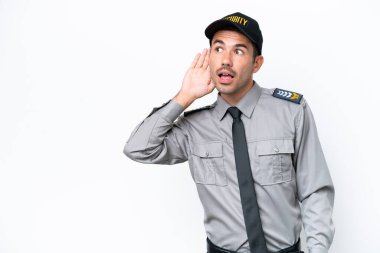 İzole edilmiş beyaz arka planda genç bir güvenlik görevlisi. Kulağına elini sürerek bir şeyler dinliyor.