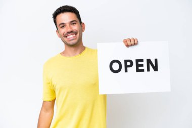 İzole edilmiş beyaz arka planda genç yakışıklı bir adam elinde mutlu bir ifadeyle açık yazılı bir pankart tutuyor.