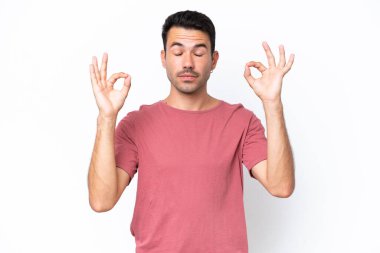 Zen pozisyonunda soyutlanmış beyaz bir geçmişi olan yakışıklı bir genç.