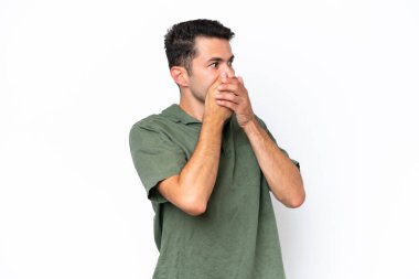 İzole edilmiş beyaz arka planda genç yakışıklı bir adam ağzını kapatıyor ve yana bakıyor.