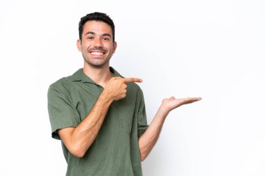 İzole edilmiş beyaz arka plan üzerinde genç yakışıklı bir adam bir ilan vermek için avucunun içinde hayali bir mekan tutuyor.