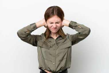 Beyaz arka planda izole edilmiş genç bir İngiliz kadın hayal kırıklığına uğramış ve kulaklarını kapatmış.