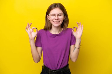 Zen pozunda sarı arka planda izole edilmiş genç İngiliz kadın.