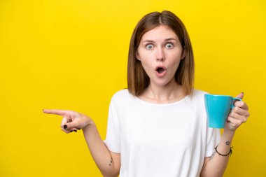 Mavi arka planda, elinde kupa tutan beyaz bir kadın.