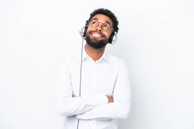 Tele pazarlamacı Brezilyalı adam beyaz arka planda izole edilmiş bir kulaklıkla çalışıyor gülümserken yukarı bakıyor