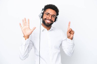Telemarketer Brazilian man working with a headset isolated on white background counting six with fingers