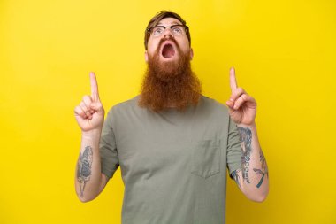 Sarı arka planda sakallı kızıl saçlı adam şaşırmış ve işaret ediyor.