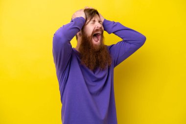 Sarı arka planda sakallı kızıl saçlı adam aşırı stresli.