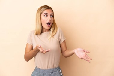 Sarışın Uruguaylı kız bej arka planda izole edilmiş.