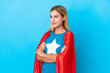 Blonde woman over isolated background in superhero costume with arms crossed