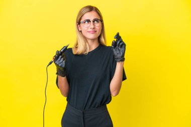 Dövme sanatçısı Uruguaylı kadın sarı arka planda izole edilmiş ve şans diliyor.