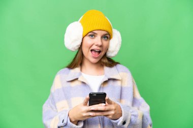 Sarışın genç bir kadın, izole edilmiş krom üzerine kışlık manşet takıyor. Arka plan şaşırmış ve mesaj gönderiyor.