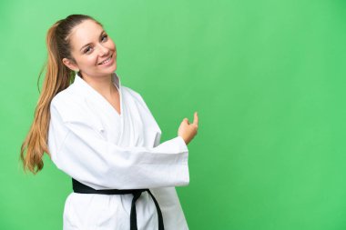 Karate yapan genç sarışın kadın izole edilmiş krom anahtar arka planı geriye doğru işaret ediyor.