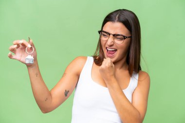 Yeşil renkli arka planda ev anahtarlarını tutan beyaz bir kadın zaferi kutluyor.