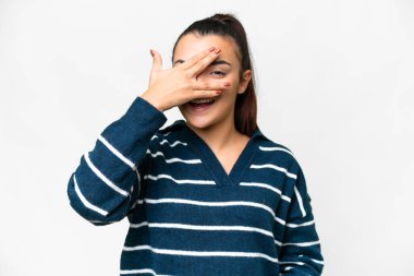 İzole edilmiş beyaz arka planda genç bir kadın. Gözleri elleriyle kaplıyor ve gülümsüyor.