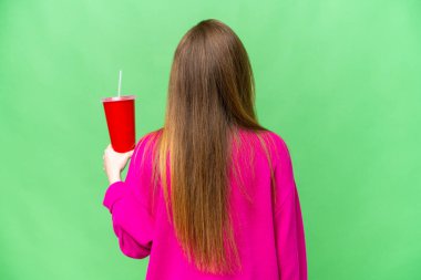 Arka planda 3 boyutlu bir film izlerken elinde soda tutan genç bir kadın.