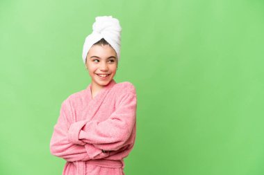 Kolları çapraz ve mutlu bir şekilde izole edilmiş krom anahtar geçmişi olan bornozlu küçük bir kız.