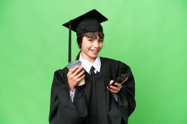 Küçük bir üniversiteli kız izole edilmiş arka planda kahve ve bir cep telefonu tutuyor.