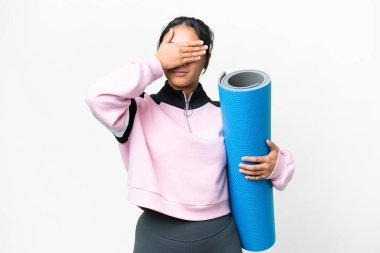 Young sport woman going to yoga classes while holding a mat over isolated white background covering eyes by hands. Do not want to see something