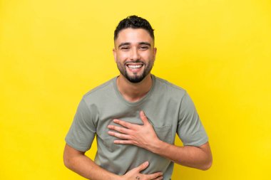 Genç Arap yakışıklı adam sarı arka planda izole edilmiş, gülümsüyor.