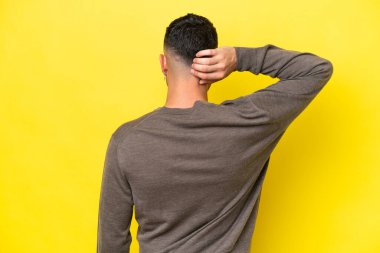 Genç Arap yakışıklı adam sarı arka planda izole edilmiş ve düşünüyor.