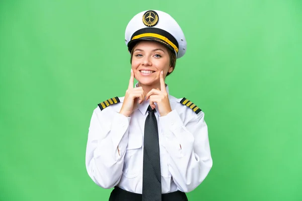 Airplane pilot woman over isolated chroma key background smiling with a happy and pleasant expression