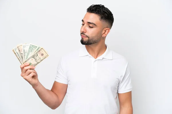 stock image Young Arab man taking a lot of money isolated on white background looking to the side