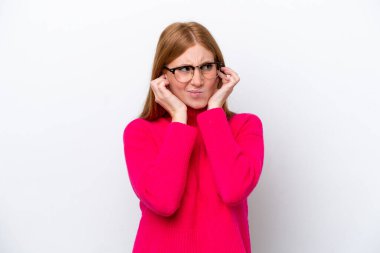 Beyaz arka planda izole edilmiş genç kızıl saçlı kadın hayal kırıklığına uğramış ve kulaklarını kapatmış.