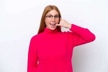 Beyaz arka planda izole edilmiş genç, kızıl saçlı bir kadın telefon hareketi yapıyor. Bana geri dönüş işareti ver.