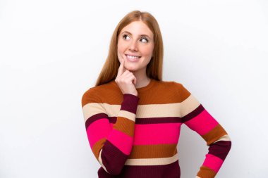 Genç kızıl saçlı kadın, beyaz arka planda izole edilmiş bir şekilde bakarken bir fikir düşünüyor.