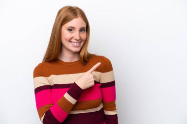 Beyaz arka planda izole edilmiş genç kızıl saçlı kadın bir ürünü sunmak için kenarı işaret ediyor.