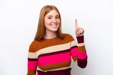 Beyaz arka planda izole edilmiş genç kızıl saçlı kadın en iyinin işareti olarak parmağını kaldırıyor ve gösteriyor.