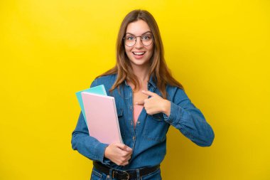 Sarı arka planda yüzü sürpriz bir ifadeyle izole edilmiş beyaz bir kadın öğrenci.