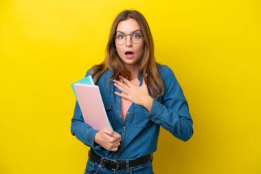 Sarı arka planda izole edilmiş genç beyaz kadın sağa bakarken şaşırdı ve şok oldu.