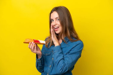 Sarı arka planda saşimi tutan beyaz bir kadın bir şeyler fısıldıyor.