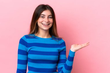 Pembe arka planda izole edilmiş genç beyaz kadın bir ilan vermek için avucunun içinde hayali bir fotokopi makinesi tutuyor.