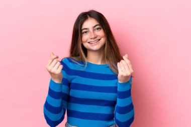 Pembe arka planda izole genç beyaz kadın para hareketi yapıyor.