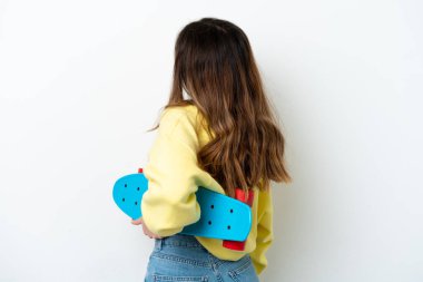 Beyaz arka planda izole edilmiş beyaz tenli genç bir kadın, arka planda kaykay yapıyor.