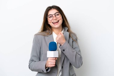 Young caucasian TV presenter woman isolated on white background celebrating a victory