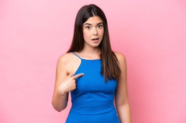 Pembe arka planda izole edilmiş genç Brezilyalı kadın kendini işaret ediyor.