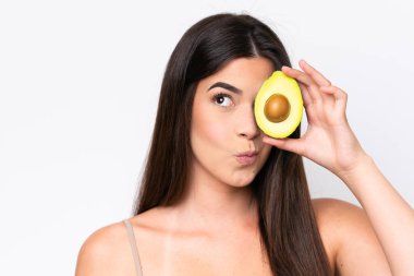 Genç Brezilyalı bir kadın beyaz arka planda izole edilmiş, elinde bir avokado tutuyor. Portreyi kapat