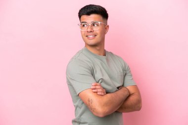 Pembe arka planda soyutlanmış beyaz tenli yakışıklı bir adam. Yan tarafa bakıyor ve gülümsüyor.