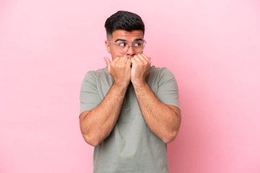 Beyaz tenli yakışıklı bir adam pembe arka planda izole edilmiş gergin ve korkmuş bir şekilde elleriyle suni teneffüs yapıyor.