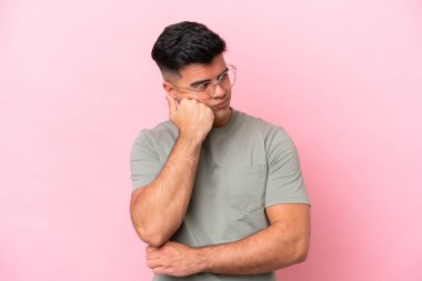 Pembe arka planda soyutlanmış, yorgun ve sıkılmış ifadesiyle beyaz, yakışıklı genç bir adam.