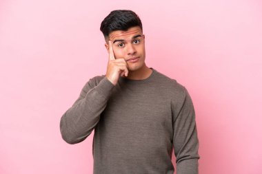 Pembe arka planda izole edilmiş beyaz, yakışıklı bir adam bir fikir düşünüyor.